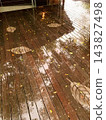 A wooden deck with a leaf pattern reflected in the rain. 143827498