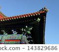 Traditional Chinese temple roof with ornate painted details against clear blue sky and decorative foreground 143829686