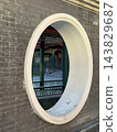 Oval architectural window framing reflection of traditional courtyard details on dark brick wall background 143829687