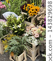 Colorful flower shop display with lilies, sunflowers, chrysanthemums, and potted plants arranged indoors 143829698