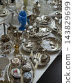 Antique silver tableware and porcelain collectibles arranged on display with ornate vintage details 143829699
