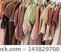 Pastel vintage clothing arranged on wooden hangers in a crowded boutique wardrobe display 143829700