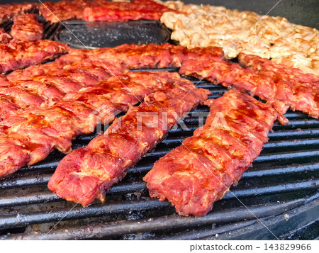 Savoring perfectly grilled ribs and chicken at a summer barbecue gathering 143829966