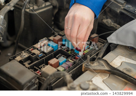 A woman removes a fuse from the car. A woman removes a fuse from the car. 143829994