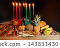 Kwanzaa kinara with seven candles and traditional harvest offerings 143831430