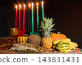 Kwanzaa celebration display with kinara, candles, fruit and harvest offerings 143831431