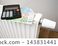 Calculator and euro banknotes on a radiator illustrating rising heating costs 143831441