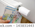 Euro banknotes beside radiator, illustrating rising household heating costs 143831443