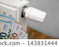 Radiator thermostat and euro banknotes illustrating rising household heating costs 143831444