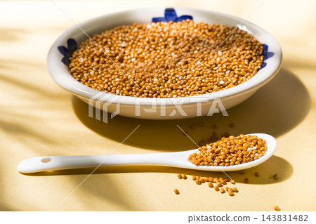 healthy grains of red millet served in a plate on yellow background 143831482