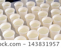 Rows of white paper water cups at sports hydration station. High angle close-up of numerous white paper cups filled with clean water arranged neatly on table at sports marathon hydration station 143831957