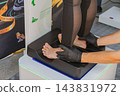 Foot assessment takes place on digital platform as specialist wearing black gloves positions participant feet. Foot assessment demonstrates physical evaluation and lower limb alignment testing 143831972
