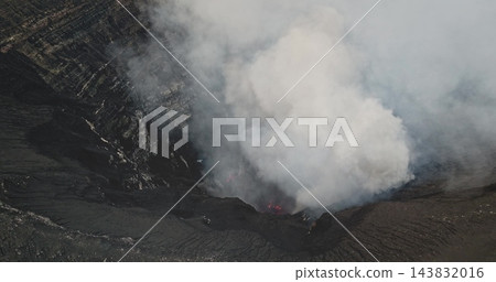 Mount Yasur crater belching thick white and gray smoke while glowing magma lights the vent, dramatic volcanic power on Tanna Island, Vanuatu, raw and explosive landscape. Aerial view drone shot 143832016