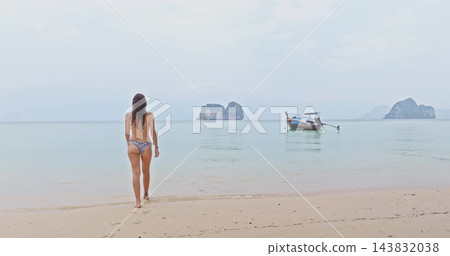 Travel to Thailand, Ko Lanta: Beautiful young woman in bikini walk sandy beach, clear turquoise water, longtail boat and iconic limestone islands in background, tropical summer vacation and relax 143832038