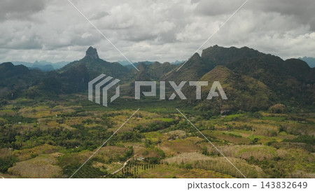 Khao Sok National Park panorama with lush rainforest, dramatic karst limestone peaks and patchwork cultivated valleys under an overcast sky, serene tropical wilderness scene. Aerial view drone flight Khao Sok National Park panorama with lush rainforest, dramatic karst limestone peaks and patchwork cultivated valleys under an overcast sky, serene tropical wilderness scene. Aerial view drone flight 143832649