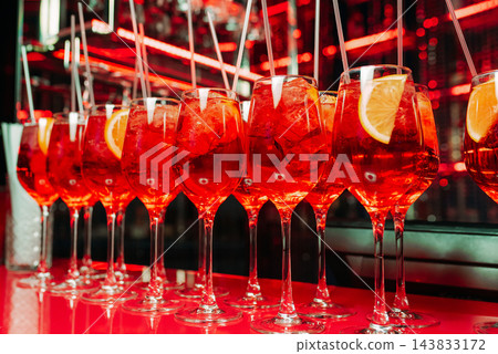Red cocktails with ice and citrus slices in a stylish bar Red cocktails with ice and citrus slices in a stylish bar 143833172
