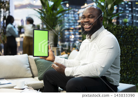 Mockup tablet used by smiling businessman next to potted plants on rooftop terrace. Chroma key device used by cheerful man working on high rise skyscraper urban lounge Mockup tablet used by smiling businessman next to potted plants on rooftop terrace. Chroma key device used by cheerful man working on high rise skyscraper urban lounge 143833390