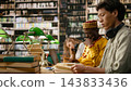 Student, reading and textbook center on young man studying open pages with headphones around his neck. Concentration, academic research and exam preparation support learning at library table. 143833436