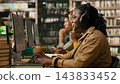 Student, computer and headphones as smiling woman types at desktop workstation beside other learners. Digital learning, concentration and productivity support research at library desks. 143833452