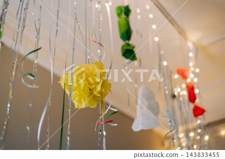 Festive party decorations with colorful paper flowers ribbons and string lights Festive party decorations with colorful paper flowers ribbons and string lights 143833455