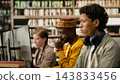 Student, headphones and computer as young man focuses on desktop monitor while classmates work nearby in library. Digital literacy, independent study and academic focus support computer learning. 143833456