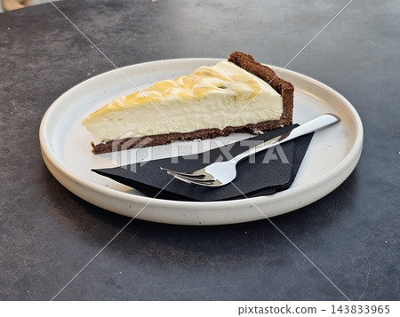 Slice of layered cheesecake served on white plate in cafe 143833965
