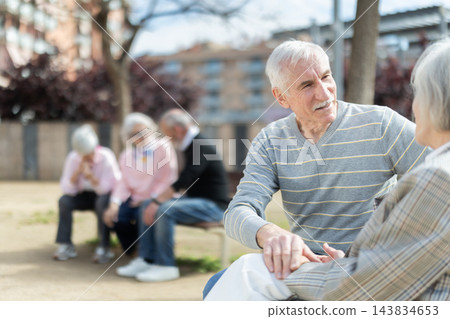 Elderly couple sitting on bench, flirting, chatting 143834653