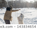 Young woman walking with fluffy samoyed dog in snowy winter park.  143834654