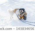 Young woman walking with fluffy samoyed dog in snowy winter park.  143834656