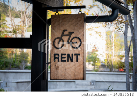 特寫鏡頭展示了一塊由木板製成的懸掛式招牌，上面有自行車圖案和“租金”字樣。 143835518