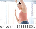 A woman dances joyfully with both hands raised. 143835801
