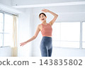 A woman in sportswear dances in a brightly lit studio. 143835802