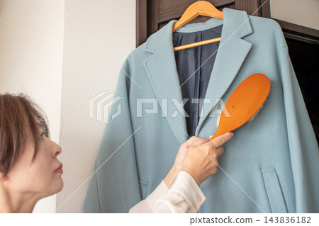 一位女士正在撣撣外套 143836182
