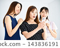 A woman looks at her smartphone in surprise, while her friends smile. 143836191