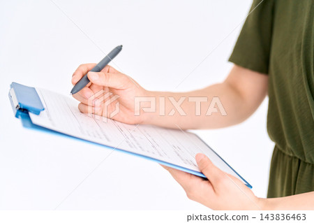一雙女人的手正用鋼筆在夾在寫字板上的文件上書寫。 143836463