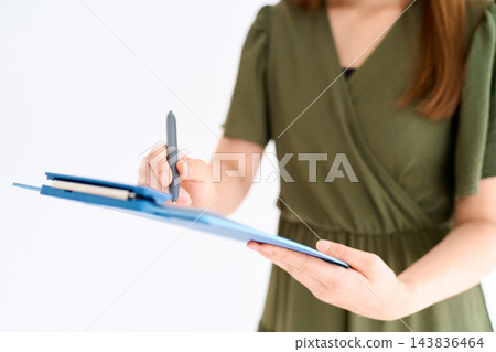 一名女子站著,正在用寫字板書寫。 一名女子站著,正在用寫字板書寫。 143836464