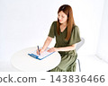 A woman sitting at a table filling out a medical questionnaire. 143836466