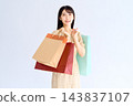 A woman in a floral dress smiles, carrying a shopping bag over her shoulder. 143837107