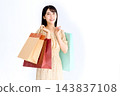 A young woman smiling while carrying shopping bags. 143837108