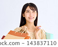A smiling woman holding a paper bag and looking diagonally upwards. 143837110