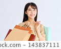 Close-up of a smiling woman holding a shopping bag. 143837111