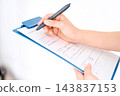 A close-up of a hand writing on a document with a pen. 143837153