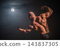 A male bodybuilder poses in shorts, showing off his back muscles. 143837305