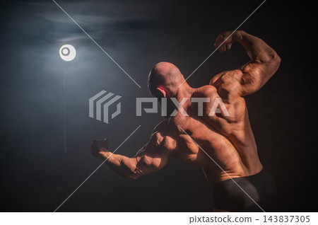 A male bodybuilder poses in shorts, showing off his back muscles. A male bodybuilder poses in shorts, showing off his back muscles. 143837305