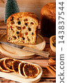 Sliced italian panettone, with a soft interior filled with raisins and candied fruit, arranged on bamboo boards atop a rustic wooden table. 143837544