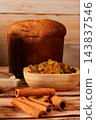 Whole Italian panettone on a bamboo tray, with candied fruits and dehydrated orange slices, on a rustic wooden table 143837546