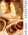 Slices of traditional Italian panettone, filled with raisins and colorful candied fruits, set on a rustic wooden Christmas table. 143837549