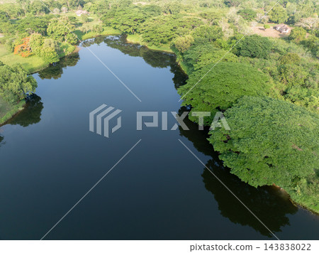 Peaceful lake among lush tropical forest with open water. Freshwater sustainability, biodiversity and natural carbon storage. Water conservation, ecosystem protection and climate resilience in nature. Peaceful lake among lush tropical forest with open water. Freshwater sustainability, biodiversity and natural carbon storage. Water conservation, ecosystem protection and climate resilience in nature. 143838022