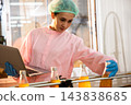 Quality inspector a woman carefully examines beverage bottles on a conveyor 143838685