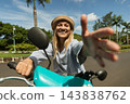 Joyful woman on a scooter rides toward the camera 143838762